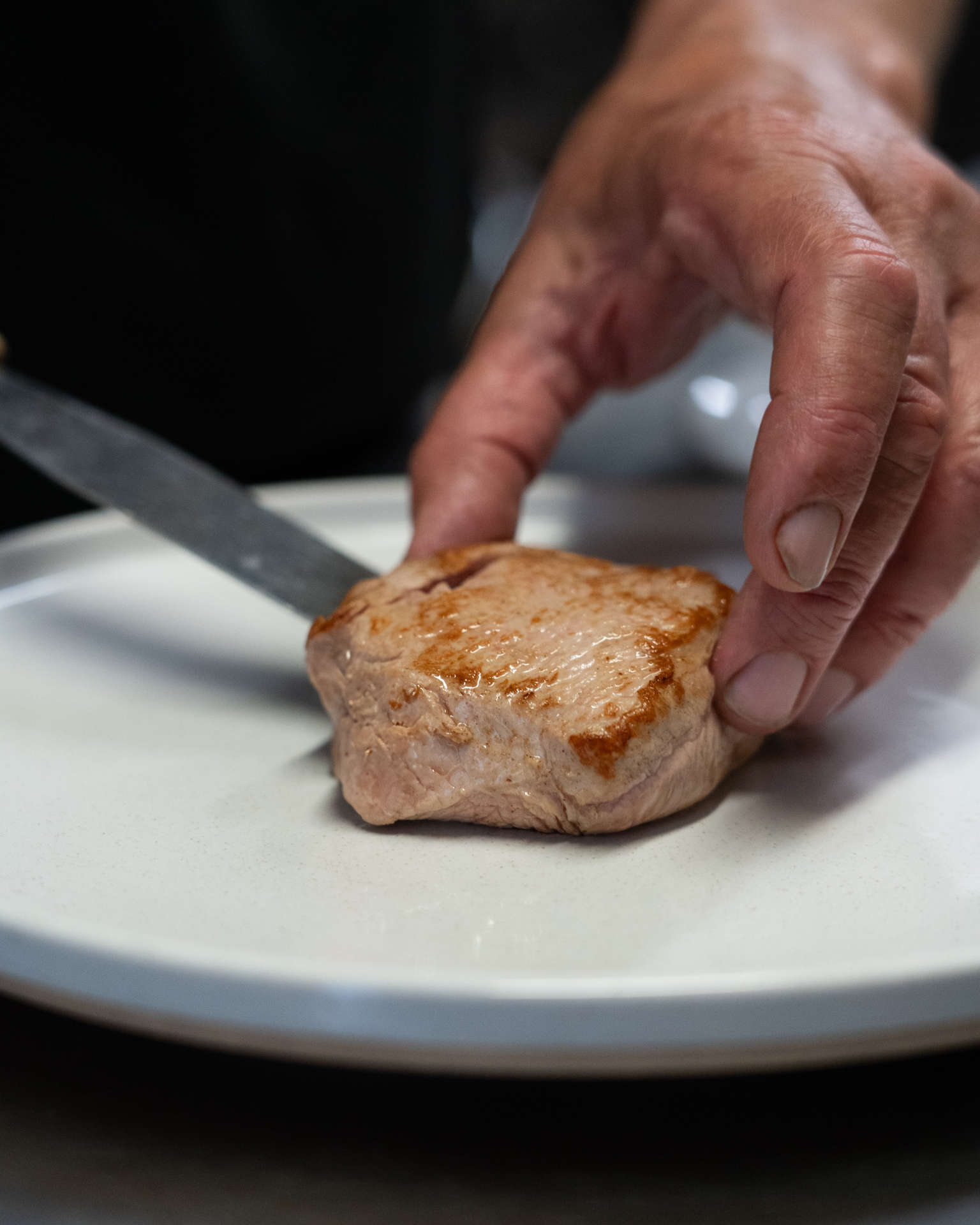 le chef du restaurant dépose un pavé de viande dans une assiette